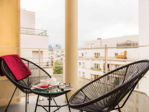 a balcony with two chairs and a table with cups at Mercure Paris Pont de Levallois Neuilly in Levallois-Perret