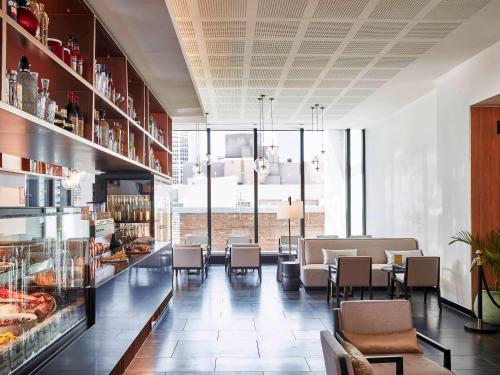 a restaurant with chairs and a counter with food at Novotel Melbourne Central in Melbourne