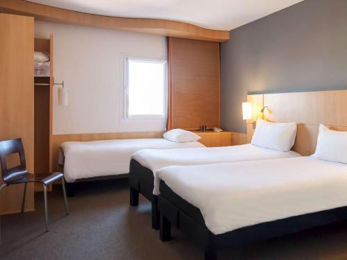 a hotel room with two beds and a chair at Ibis Praha Old Town in Prague