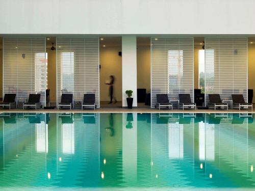 a person standing next to a swimming pool at Pullman Kuching in Kuching