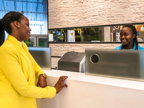 two women standing at a counter with a computer at ibis Styles - Nairobi, Westlands in Nairobi
