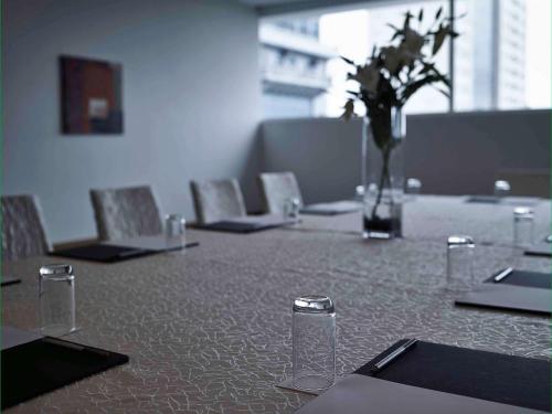 a table with chairs and a vase with flowers on it at Pullman Kuching in Kuching