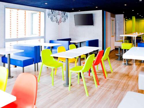 a dining room with tables and chairs and a tv at ibis budget Metz Technopole in Metz