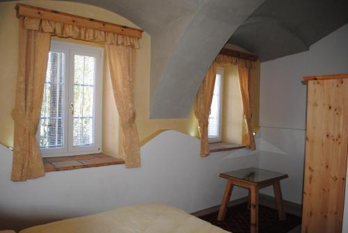 a bedroom with two windows and a bed and a table at Gartler's Appartements in Kalsdorf bei Graz