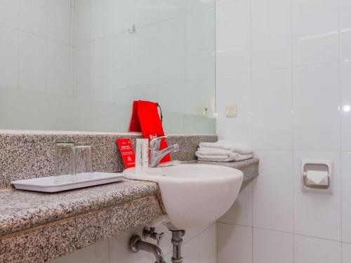 La salle de bains est pourvue d'un lavabo blanc et d'un miroir. dans l'établissement RedDoorz near Simpang Dago 2, à Bandung