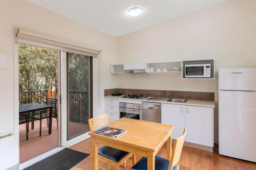 a kitchen with a wooden table and a dining room at Ramada Resort by Wyndham Phillip Island in Cowes