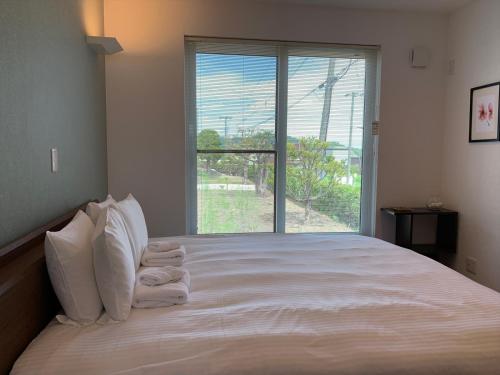 a bedroom with a bed with white pillows and a window at Diamond Dust Furano in Furano