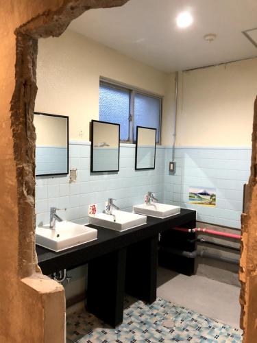 a public bathroom with three sinks and mirrors at Yanbaru Hostel in Kunigami