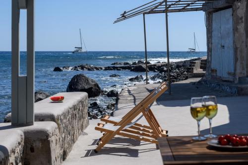 a table with a glass of wine next to the ocean at Sublime Villa & Caves in Akrotiri