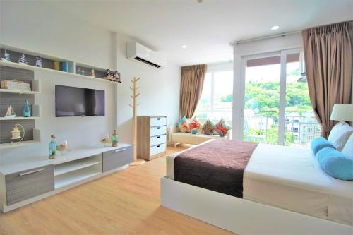 een slaapkamer met een groot bed en een televisie bij Ozone Condotel Kata Beach by PHR in Kata Beach