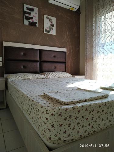 um quarto com uma cama com colcha floral e uma janela em LAZAROS APARTMENTS em Olympiakí Aktí