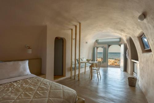 Sublime Villa & Caves في أكروتيري: غرفة نوم بسرير وطاولة مع كراسي