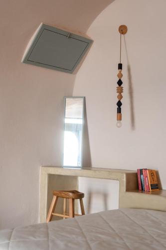 a bedroom with a bed and a mirror and a stool at Sublime Villa & Caves in Akrotiri
