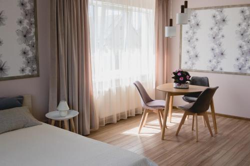 ein Hotelzimmer mit einem Tisch, Stühlen und einem Fenster in der Unterkunft Apartments in Joniškis in Joniškis