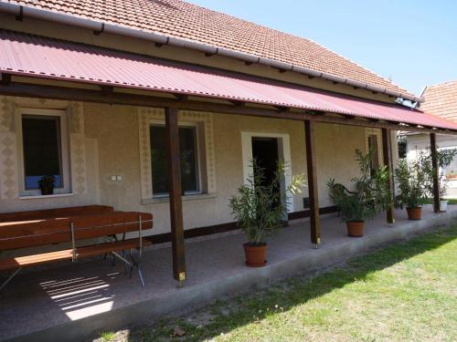 a building with a bench and potted plants on it at István Vendégház in Mórahalom