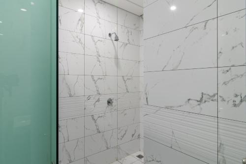 a bathroom with white marble walls and a shower at RedDoorz Plus near Senayan City in Jakarta