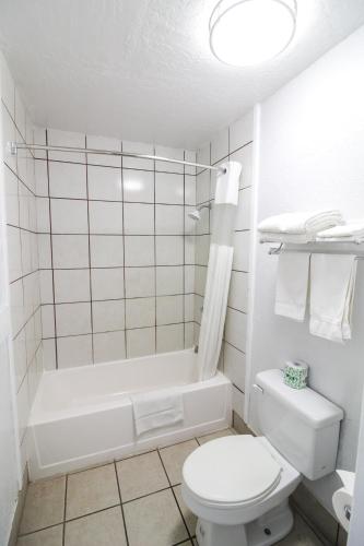 a white bathroom with a toilet and a bath tub at Stage Stop Inn Williams in Williams