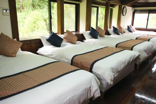 a row of beds in a room with windows at House-Uma Kensyukan -SEVEN Hotels and Resorts- in Onna
