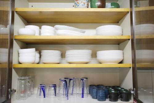 a cabinet filled with plates and bowls on shelves at House-Uma Kensyukan -SEVEN Hotels and Resorts- in Onna