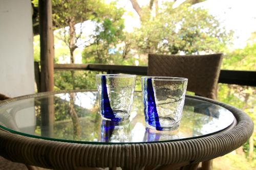 two glasses are sitting on a glass table at House-Uma Kensyukan -SEVEN Hotels and Resorts- in Onna