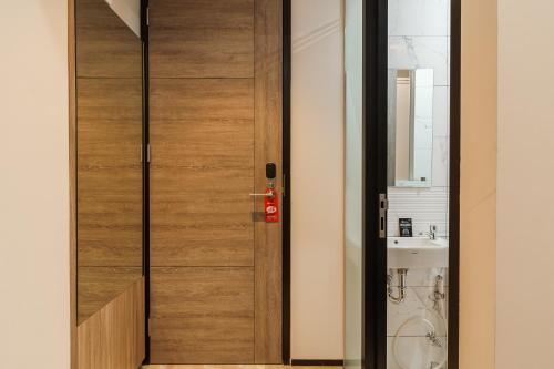 a wooden door in a bathroom with a sink at RedDoorz Plus near Senayan City in Jakarta