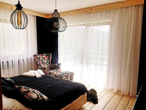 a bedroom with a bed and a chair and a window at Otuleni Tatrami Apartments in Kościelisko