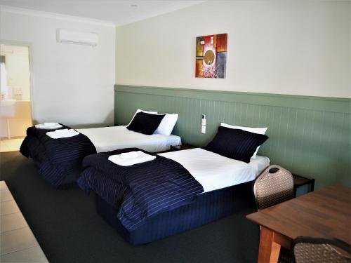 Habitación de hotel con 2 camas y mesa en Pittsworth Motor Inn, en Pittsworth