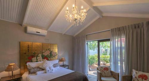 a bedroom with a large bed and a chandelier at Slaley Country House in Stellenbosch