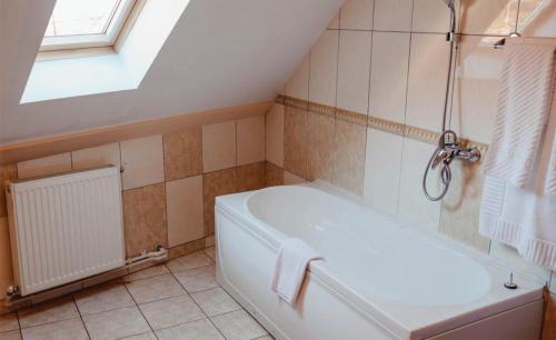 a bathroom with a white bath tub and a window at Pensiunea La Cetate in Târgu Neamț