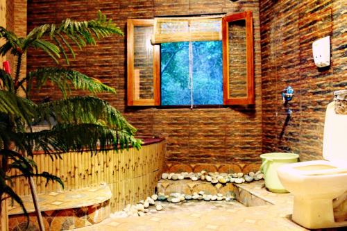 La salle de bains est pourvue de toilettes et d'une fenêtre. dans l'établissement Hill Top Swiss Cottage, à Rishikesh