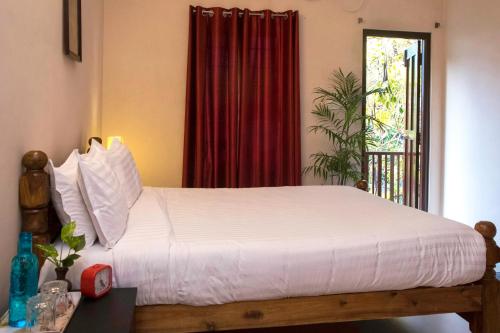 a bedroom with a large white bed with a window at Villa Gomez in Puducherry