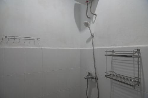 a shower in a white bathroom with a shower head at RedDoorz Plus near Cambridge City Square 2 Medan in Medan
