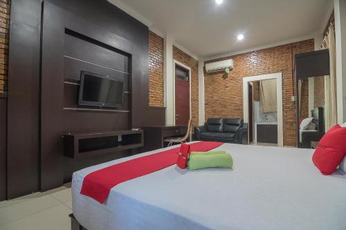 a hotel room with a bed and a television at RedDoorz Plus near Cambridge City Square 2 Medan in Medan