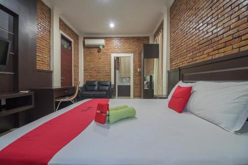 a bedroom with a large white bed with red and green pillows at RedDoorz Plus near Cambridge City Square 2 Medan in Medan