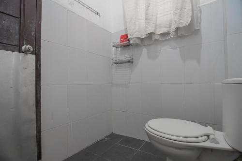 a white bathroom with a toilet and a towel at RedDoorz Plus near Cambridge City Square 2 Medan in Medan