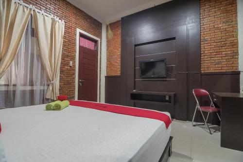 a bedroom with a bed and a tv on a wall at RedDoorz Plus near Cambridge City Square 2 Medan in Medan