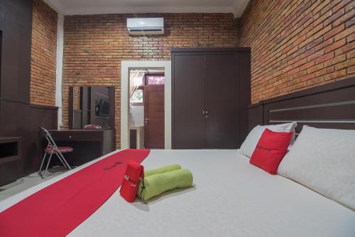 a bedroom with a large bed with red and green pillows at RedDoorz Plus near Cambridge City Square 2 Medan in Medan
