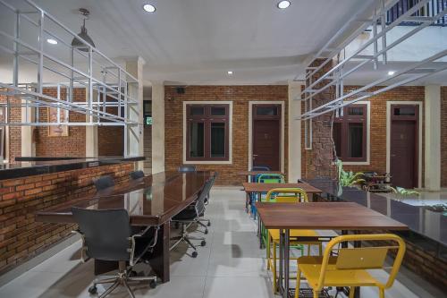a room with tables and chairs and a brick wall at RedDoorz Plus near Cambridge City Square 2 Medan in Medan