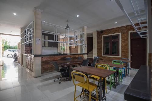 a dining room with tables and chairs and a brick wall at RedDoorz Plus near Cambridge City Square 2 Medan in Medan
