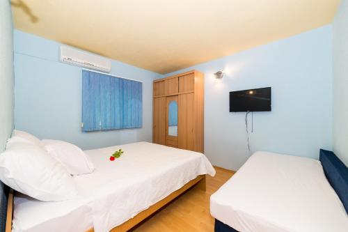 a bedroom with two beds with white sheets and a television at Villa Gorica Apartments Ražanj in Ražanj