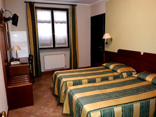 a hotel room with two beds and a window at La Cascina Di Villa Due in Narzole