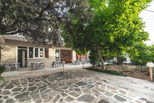 a stone walkway with tables and chairs in front of a building at Hotel Ikaros in Archangelos