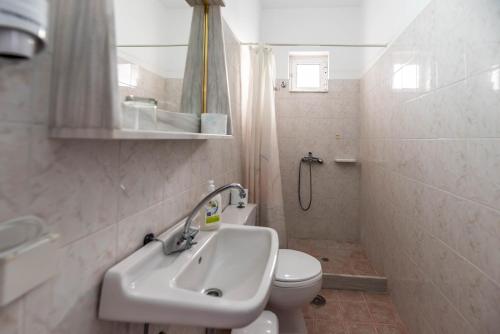 a white bathroom with a sink and a toilet at Hotel Ikaros in Archangelos