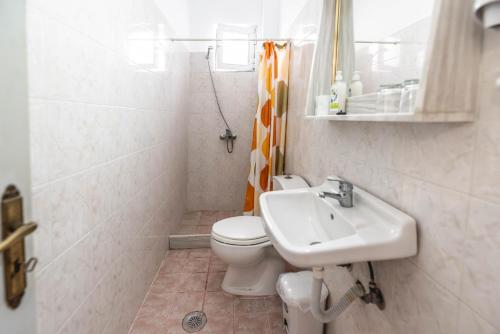 a white bathroom with a toilet and a sink at Hotel Ikaros in Archangelos