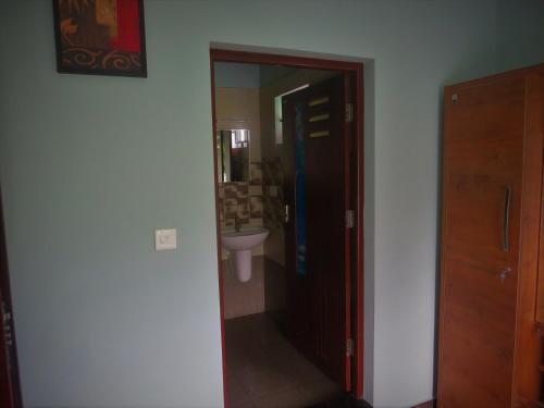 La salle de bains est pourvue d'une porte menant à un lavabo. dans l'établissement Honeybee residency Vagamon, à Vagamon