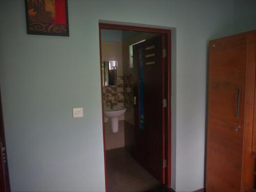 a bathroom with a door leading to a sink at Honeybee residency Vagamon in Vagamon
