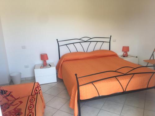 a bedroom with a bed with an orange comforter and two lamps at B&B Gigi’ in Marina di Massa