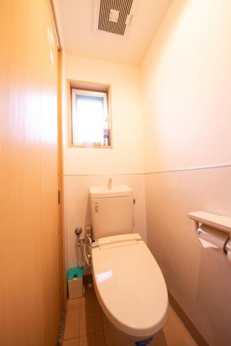 a small bathroom with a toilet and a window at Pine House in ISHIGAKI in Ishigaki Island