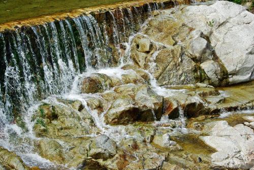 a waterfall in a park with rocks and water at Els Caçadors de Maçanet in Maçanet de Cabrenys