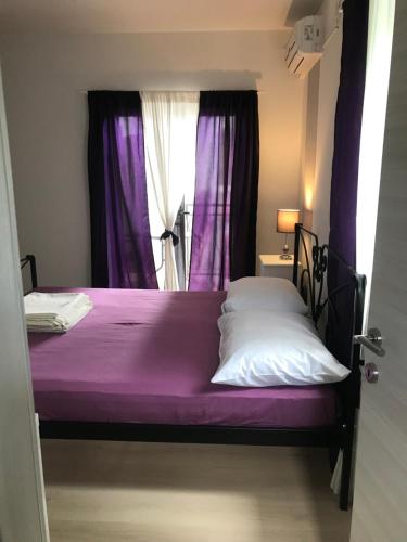 a bed with purple sheets and a window with purple curtains at Rooms Milena in Senj